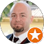 A bald man with a beard is wearing a suit and tie.